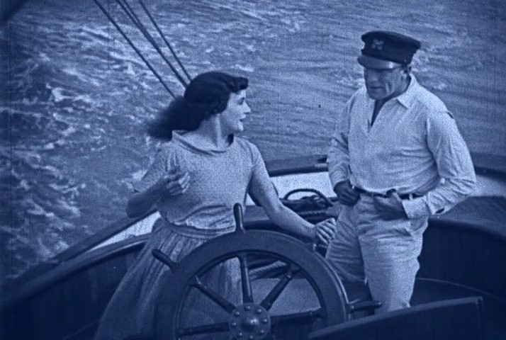 Actors in Yankee's cockpit at the wheel in a tinted frame from Wild Oranges